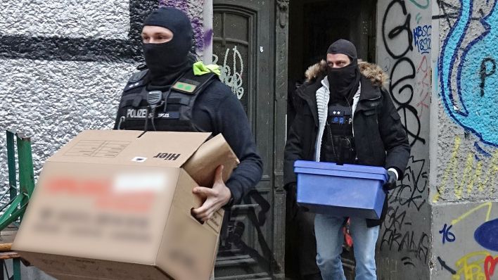 Polizeibeamte tragen am 20.12.2023 während einer Durchsuchungsaktion Kartons aus einem Mietshaus in Berlin. (Quelle: dpa-Bildfunk/Paul Zinken)