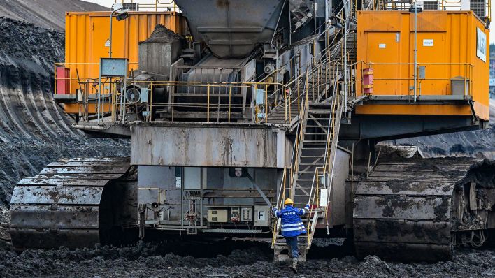 Ein Mitarbeiter der Lausitz Energie Bergbau AG (LEAG) klettert auf eine riesige Fördermaschine am Kohleflöz im Braunkohletagebau Jänschwalde. (Quelle: dpa/Patrick Pleul)