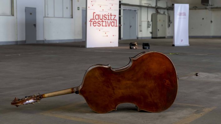Kontrabass liegt vor Lausitz-Festival-Transparent (Bild: imago images/Rainer Weisflog)