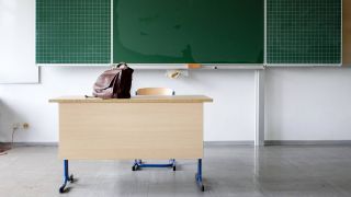 Eine Ledertasche steht auf dem Lehrertisch in einem Klassenzimmer. (Quelle: imago-images/Ute Grabowsky)
