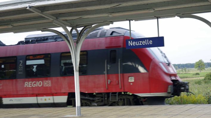 Archivbild: Bahnhofsschild und Zug am Bahnhof Neuzelle. (Quelle: imago images/Steinach)