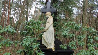 Detailreich verzierter Grabstein mit Kreuz und weiblicher Statue, Südwestkirchhof Stahnsdorf (Quelle: rbb/Sebastian Hampf)