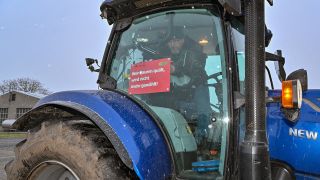 Frank Schuhmacher, Produktionsleiter Landgesellschaft Lebus GmbH, befestigt in seinem Traktor ein Transparent mit der Aufschrift «Wer Bauern quält, wird nicht mehr gewählt!» (Quelle: dpa/Pleul)