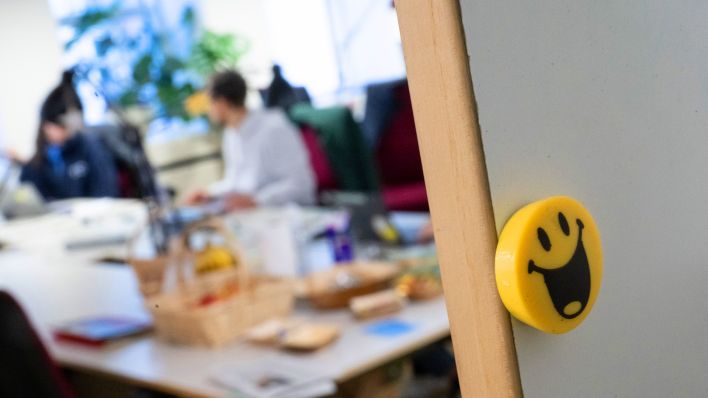 Symbolbild: Ein lachender Smilie ist an einer magnetischen Wand in einem Büro. (Quelle: dpa/Sebastian Gollnow)