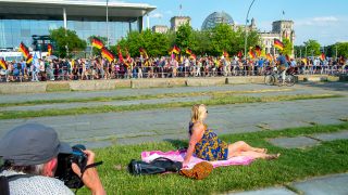 Archivbild: Eine Frau und ein Fotograf beobachten am 09.06.2018 Demo-Teilnehmer die mit Deutschlandfahnen vor dem Reichstag. (Quelle: dpa/Stefan Jaitner)