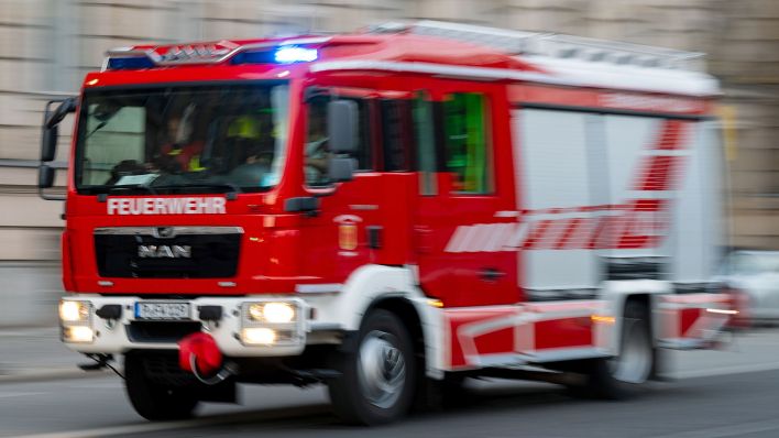 Symbolbild: Ein Feuerwehrauto mit eingeschaltetem Blaulicht fährt zum Einsatz. (Quelle: dpa/Skolimowska)
