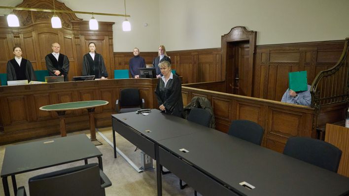 Archivbild: Ein 39-jähriger Angklagter (r) sitzt im Landgericht Berlin und verbirgt sein Gesicht. Rund sieben Monate nach dem Messerangriff auf zwei Mädchen auf einem Schulhof in Berlin-Neukölln begann der Prozess gegen den Täter. (Quelle: dpa/Carstensen)