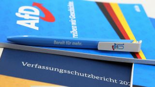 Symbolbild: Ein Bleistift der Partei Alternative für Deutschland AfD liegt auf einem Verfassungsschutzbericht. (Quelle: IMAGO/Hanno Bode)