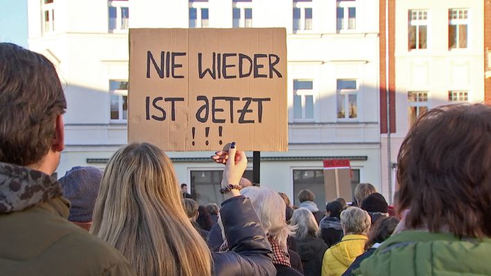 Eine Teilnehmerin auf einer Demonstration in Finsterwalde am 28.01.2023 hält ein Schild "Nie wieder ist jetzt" in die Höhe. (Quelle: rbb)