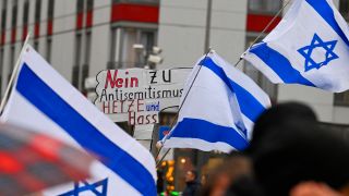 Symbolbild: Israelische Fahnen und ein Plakat mit der Aufschrift «Nein zu Antisemitismus, Hetze und Hass». (Quelle: dpa/Roberto Pfeil)