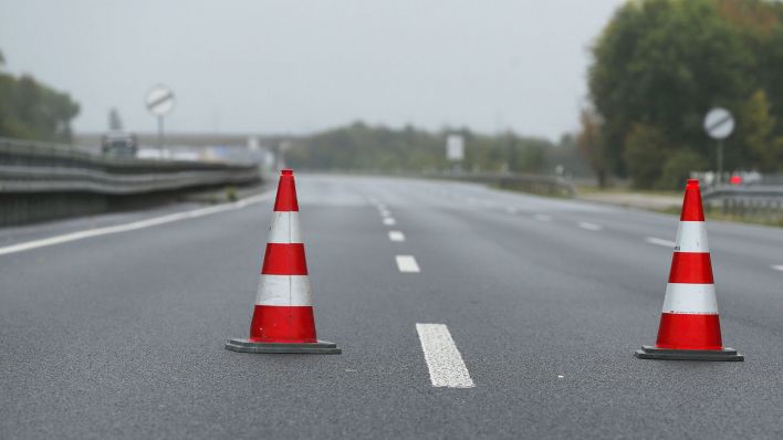 Symbolbild: 2 Verkehrshütchen stehen mitten auf der gesperrte Autobahn. (Quelle: dpa/Young)