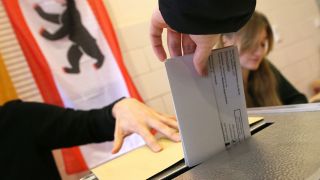 Symbolbild: Eine Frau gibt ihre Stimme für die Wahl in Berlin ab und wirft ihren Wahlzettel in die Wahlurne. (Quelle: dpa/Kumm)