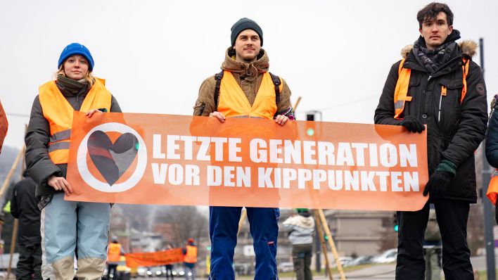 Archivbild: Aktivist:innen der Letzten Generation halten ein Banner mit der Aufschrift "Vor den Kippunkten" hoch. (Quelle: dpa/Stroh)