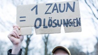 Demonstrant mit Schild "1 Zaun = 0 Lösungen" bei einem Rundgang in Begleitung der Bezirksbürgermeisterin und Mitgliedern des Bezirksamts durch den Görlitzer Park. (Quelle: dpa/Ben Kriemann)