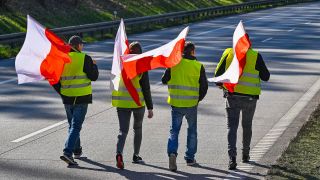 25.02.2024, Polen, Slubice: Teilnehmer einer Demonstration gehen mit der Nationalfahne von Polen auf der gesperrten Autostrada A2 (Europastraﬂe 30) in Richtung deutsch-polnische Grenze.(Quelle:dpa/P.Pleul)