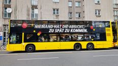 Symbolbild:Ein Bus der BVG fährt durch Kreuzberg. Auf dem Bus steht, als Abwandlung eines Zitats von Erich Honecker, "Niemand hat die Absicht, zu spät zu kommen".(Quelle:picture alliance/dpa/W.Steinberg)