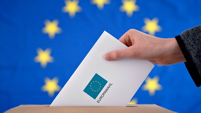 Symboolafbeelding: Een Wahlbrief werd in een Wahlurne geplaatst, op de achtergrond van een EU-vlag.  (Quelle: dpa/Panama)