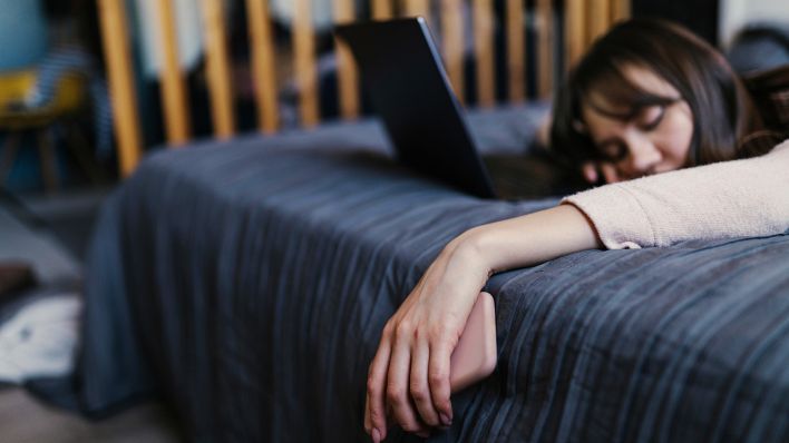 Symbolbild:Eine Frau schläft vor ihrem aufgeklappten Notebook mit Handy in der Hand.(Quelle:picture alliance/Westend61/A.Nelen)