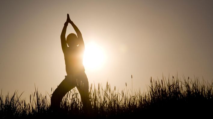 Frau macht Yoga im Sonnenaufgang (Quelle: Shotshop/picture alliance/Tobias Ott)