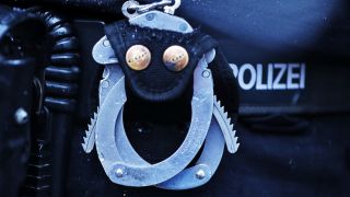 Symbolbild: Handschellen und Handfeuerwaffe im Pistolen Holster am Gürtel eines Polizisten in Nahaufnahme.(Quelle: dpa/Maximilian Koch)