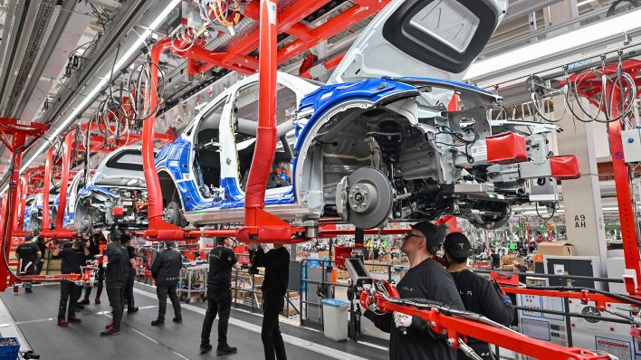 Symbolbild: Mitarbeiter der Tesla Gigafactory Berlin Brandenburg arbeiten an einer Fertigungslinie eines Elektrofahrzeuges vom Typ Model Y. (Quelle: dpa/Pleul)