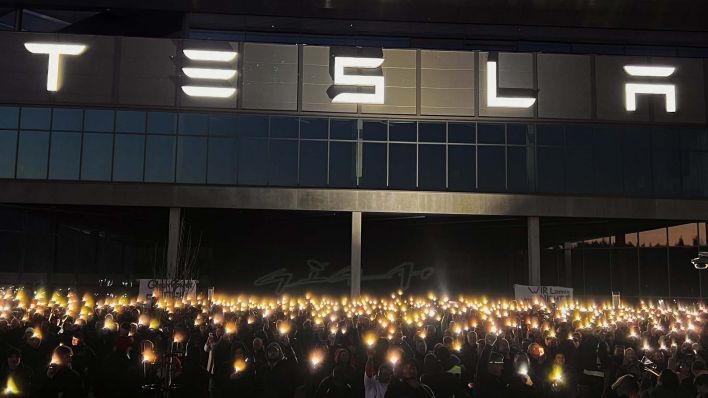 Mitarbeiter von Tesla stehen im dunkeln vor dem Werk und halten Lichter in der Hand. Bild: rbb / Martin Krauß
