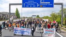 Teilnehmer der Demonstration eines Bündnisses von Initiativen und Verbänden gegen Weiterbau der A100 gehen auf der Autobahn und tragen Plakate und Transparente am 21.04.2024.(Quelle: picture alliance/dpa/Christophe Gateau)