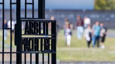 Symbolbild:Blick auf das Eingangstor mit der Inschrift "Arbeit macht frei", im Hintergrund gehen Besucher über das Gelände des ehemaligen KZ Sachsenhausen.(Quelle:picture alliance/dpa/H.P.Albert)