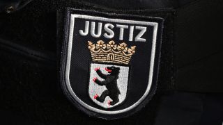 Symbolbild: Das Logo auf der Uniform eines Justizbeamter im Berliner Landgericht. (Quelle: dpa/Soeren Stache)