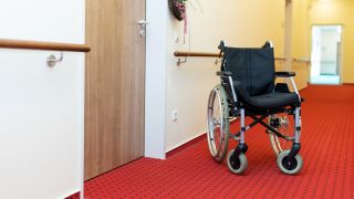 Symbolbild: Auf einem Flur in einem Altenheim steht ein Rollstuhl vor der Zimmertür. (Quelle: dpa/Gelhot)