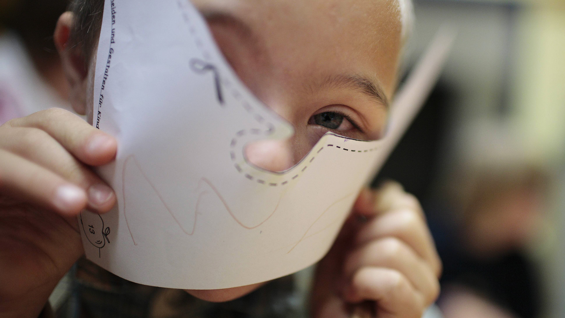 Symbolbild:Ein Kind hält sich eine Maske vor das Gesicht.(Quelle:imago images/photothek/U.Grabowsky)