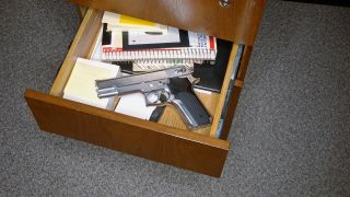 Symbolbild:Eine Pistole liegt mit Schreibwaren in einer Schublade.(Quelle:imago images/Wirestock)