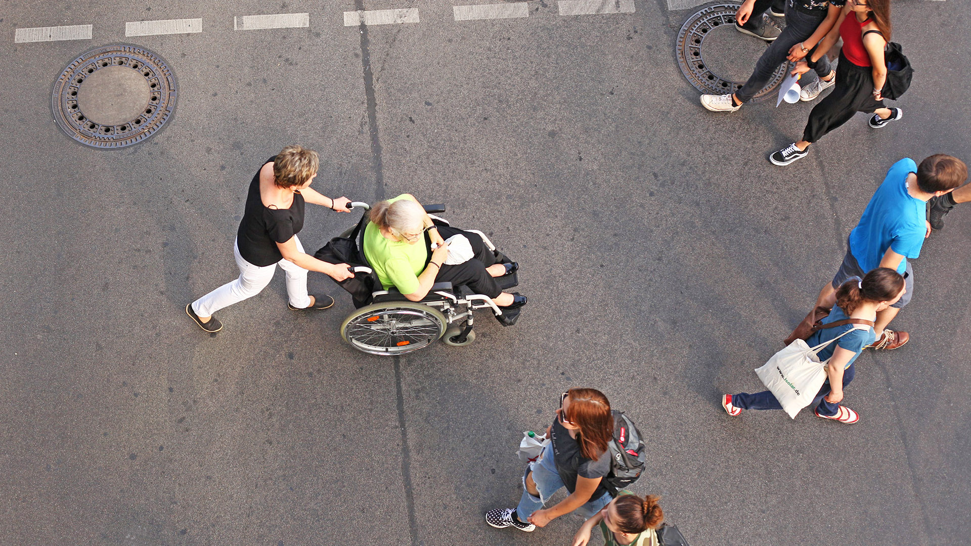 Symbolbild: Eine Frau schiebt eine Seniorin im Rollstuhl auf einer Einkaufsstraße in Berlin Friedenau über eine Ampelkreuzung am 16.09.2018. (Quelle: picture alliance/Wolfram Steinberg)