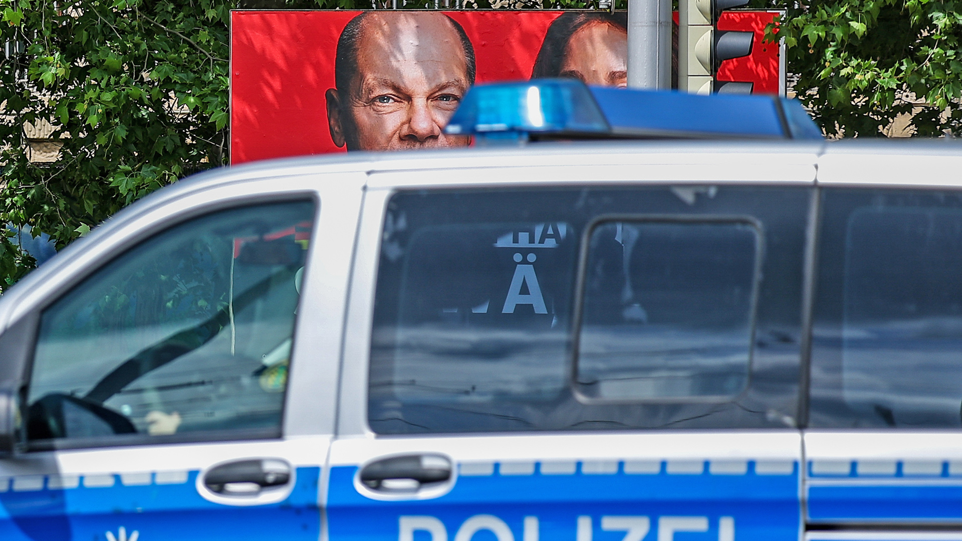 Symbolbild: Ein Streifenwagen der Polizei fährt an einem Europawahlplakat der SPD mit einem Foto von Bundeskanzler Scholz und Katarina Barley vorbei.(Quelle: dpa/Jan Woitas)