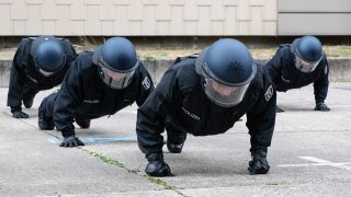 Polizeischüler machen in voller Montur Liegestütze. (Quelle: dpa/Paul Zinken)