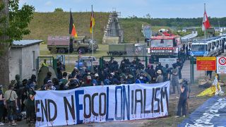 Aktivisten blockieren eine Zufahrt zum Flugplatz Neuhardenberg. (Quelle: dpa/Patrick Pleul)