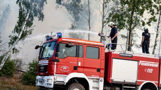 Archivbild: Einsatzkräfte der Feuerwehr bekämpfen in einem Waldstück in Brandenburg das Feuer. (Quelle: dpa/Sommer)