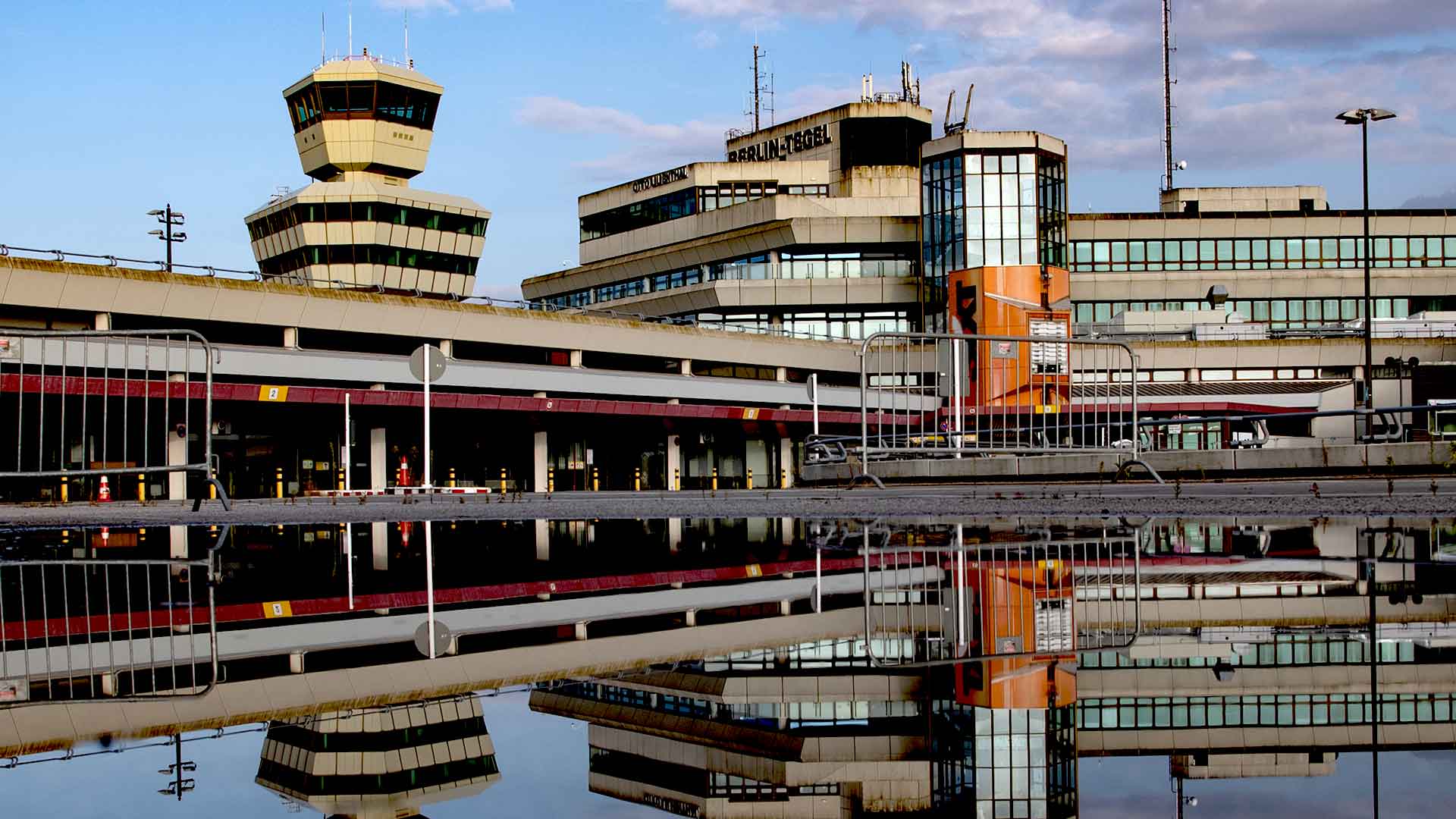 er Tower und das Gebäude des ehemaligen Flughafen Tegel spiegeln sich in einer Regenpfütze. (Foto: dpa)