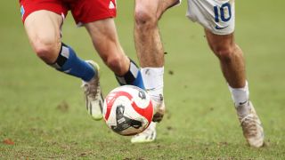 Zwei Fußballspieler, von denen nur die Beine zu sehen sind, jagen einem Ball hinterher (Bild: Imago Images/Hanno Bode)