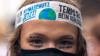 Symbolbild:Eine Klimaaktivistin hat sich neben einer Kopfbinde auch Forderungen um ihre AUgen geschminkt.(Quelle:imago images/Y.Tang)
