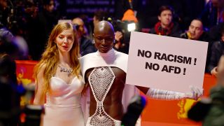 15.02.2024, Berlin: Papis Loveday (r) steht am Eröffnungsabend der Berlinale mit einem Protestschild "No Racism ! No AFD !". (Quelle: dpa/Monika Skolimowska)