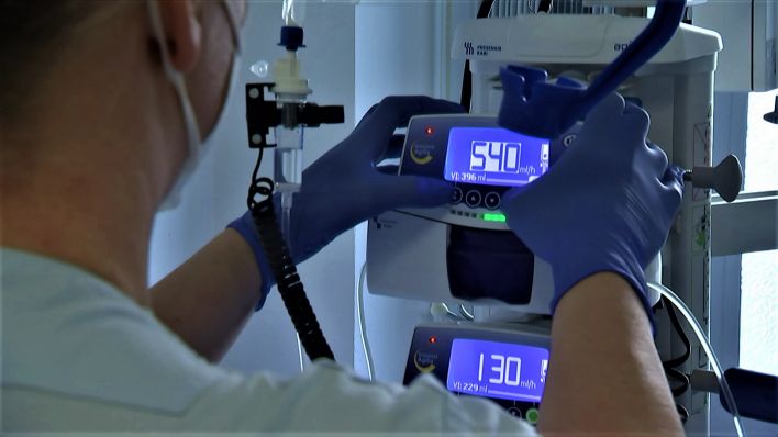 Krankenpfleger überprüft Geräte am Bett eines Corona-Patienten