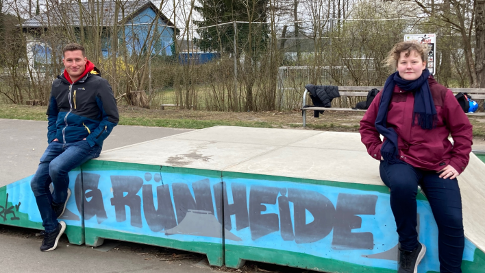 Zwei Jugendliche sitzen auf einem Skaterpodest, darauf steht Grünheide