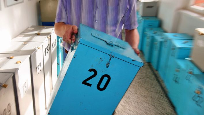 Ein Mann trägt eine Wahlurne (Symbolbild: dpa/Rehder)