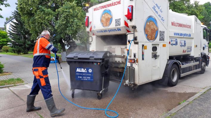 Ein Mann sprüht in Cottbus eine dreckige Mülltonne mit Wasser ab (Foto: rbb/Schomber)