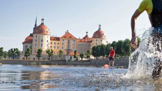 Ein Teilnehmer des Moritzburger Schloss-Triathlon läuft vor der Kulisse des Schloss Moritzburg aus dem Schlossteich (Foto: dpa/Kahnert)