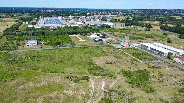 Auf dieser noch leeren Fläche am Rande eines Industriegebietes ist die Ansiedlung eines Werkes des kanadischen Rohstoff-Unternehmens Rock Tech Lithium geplant (Luftaufnahme mit einer Drohne) (Foto: dpa/Pleul)