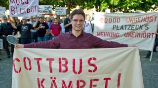 Student Jonas Schindler protestiert mit einem Transparent am 18.09.2012 vor dem Stadthaus in Cottbus gegen die Zusammenlegung der BTU in Cottbus und der Hochschule Lausitz in Senftenberg (Foto: dpa/Pleul)