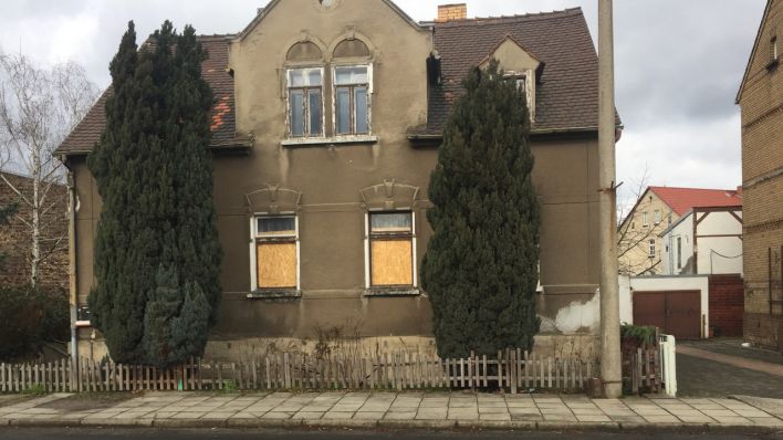Ein Haus am Bahnhof in Ruhland, dessen Fenster mit Holzplatten abgedeckt sind. Die Scheiben waren bei der Sprengung einer Bombe geborsten.