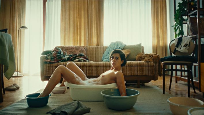 Anna (Ioana Iacob) liegt nackt wie ein Octopus in einer zu kleinen Badewanne im Zimmer. Hände und Füße in Schüsseln mit Wasser. (Bild: rbb/Jan Mayntz)